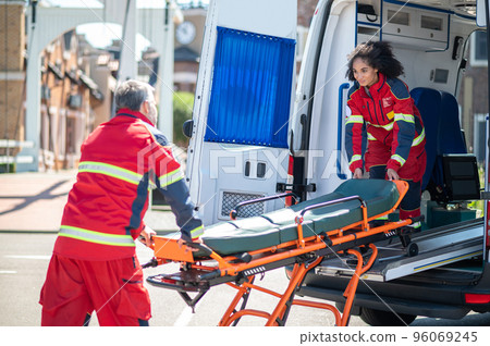 Paramedical workers taking a stretcher out of the EMS vehicle 96069245