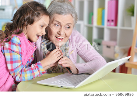 portrait of grandmother and daughter singing karaoke 96069986