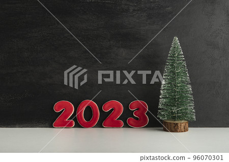 Artificial Christmas tree and red numbers 2023 on black background. New year concept. Copy space 96070301