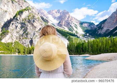 Young woman in white dress and hat enjoying the picturesque lake Braies and Dolomites Alps, Italy. 96070476