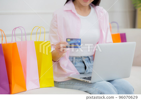 Young asian woman sitting on sofa using laptop computer shopping online with credit card. 96070629