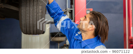 Young man is mechanic repair tires wheel car in the garage with professional, auto service. 96071122