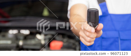 Closeup hands of mechanic giving key after repair car at garage, auto service. Closeup hands of mechanic giving key after repair car at garage, auto service. 96071123