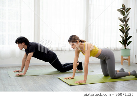 Young woman and man practicing workout with posing plank on mat while motivation. Young woman and man practicing workout with posing plank on mat while motivation. 96071125