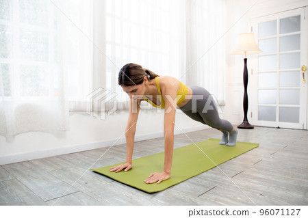Young caucasian woman practicing workout exercise with plank stretching muscle leg and hands. Young caucasian woman practicing workout exercise with plank stretching muscle leg and hands. 96071127
