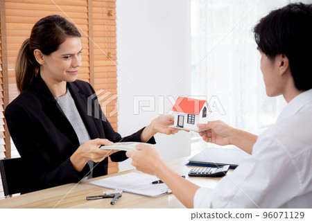 Young realtor woman giving house model to hands customer while client giving money. Young realtor woman giving house model to hands customer while client giving money. 96071129