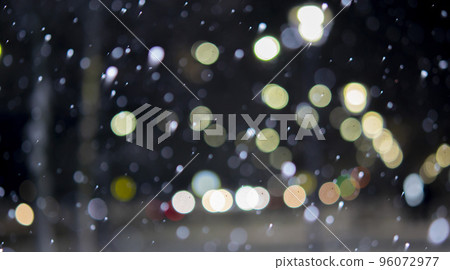 Blurred background. City view, lights, falling snow, night, street, bokeh spots of headlights of moving cars. Diffuse Urban backdrop winter scenery of street in city at night. Lantern light, snowfall 96072977