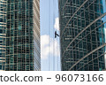 Industrial mountaineering. Window cleaner performs work between two skyscrapers 96073166