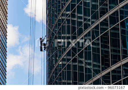 Industrial mountaineering. Window cleaner performs work between two skyscrapers 96073167