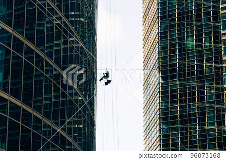 Industrial mountaineering. Window cleaner performs work between two skyscrapers 96073168