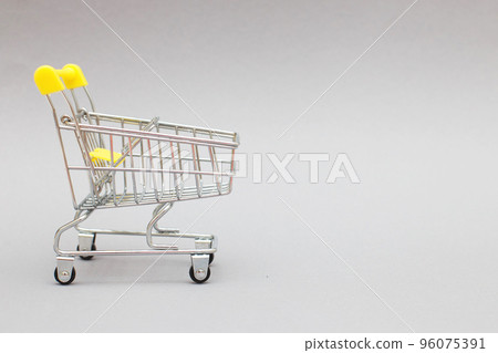 The metal shopping cart on a grey background. The metal shopping cart on a grey background. 96075391