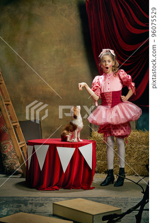 Circus trainer. Portrait of little cute beautiful girl in festive dress training funny doggy at vintage circus. Holidays, dreams, art, fashion, vintage style Circus trainer. Portrait of little cute beautiful girl in festive dress training funny doggy at vintage circus. Holidays, dreams, art, fashion, vintage style 96075529