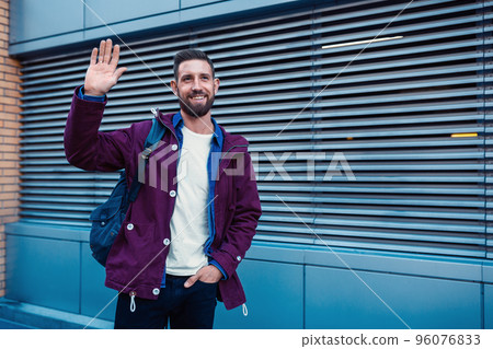 Half length portrait of handsome bearded man dressed in fashionable clothes standing on street. 96076833