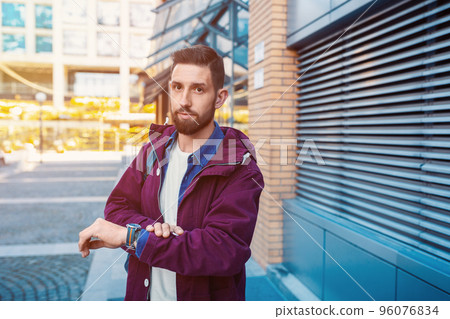 Man stand on the city street, look on his watch and around Man stand on the city street, look on his watch and around 96076834
