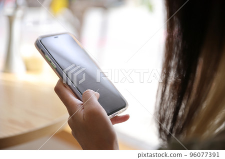 Woman hand using a smartphone for Stock exchange trading online in the coffee shop, business concept Woman hand using a smartphone for Stock exchange trading online in the coffee shop, business concept 96077391
