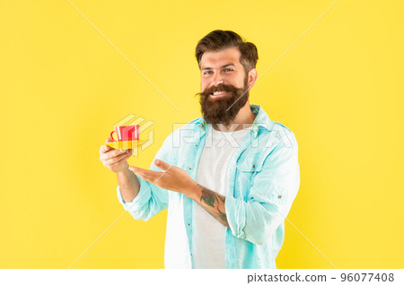 glad unshaven man in shirt showing coffee on yellow backdrop, beverage 96077408