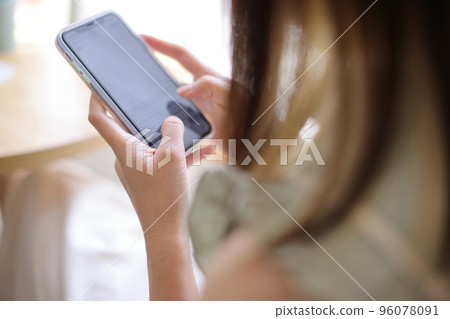 Woman hand using a smartphone for Stock exchange trading online in the coffee shop, business concept Woman hand using a smartphone for Stock exchange trading online in the coffee shop, business concept 96078091