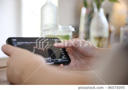Woman hand using a smartphone for Stock exchange trading online in the coffee shop, business concept 96078095