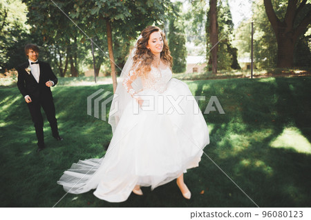 Beautiful romantic wedding couple of newlyweds hugging in park on sunset Beautiful romantic wedding couple of newlyweds hugging in park on sunset 96080123