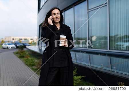 a woman specialist in dealership goes to the office talking on a mobile phone with a glass of coffee 96081700