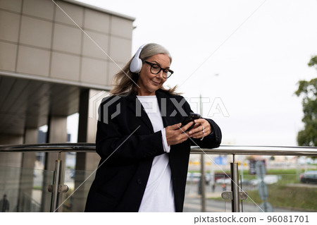 woman economist for contract and claim work, in headphones on the terrace of the office outside woman economist for contract and claim work, in headphones on the terrace of the office outside 96081701
