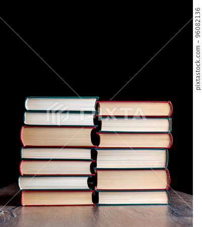 Two stacks of hardback books against a dark background. Two stacks of hardback books against a dark background. 96082136