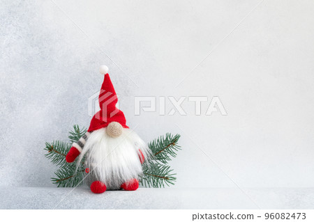 Christmas gnome in red cap with fir branch holiday invitation card on light winter background Christmas gnome in red cap with fir branch holiday invitation card on light winter background 96082473