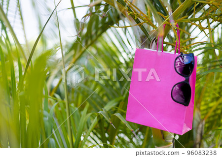 Pink paper bag with sunglasses on a palm leave. Mockup. Pink paper bag with sunglasses on a palm leave. Mockup. 96083238