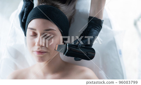Top view of a woman on an ultrasonic cleaning procedure. Hardware cosmetology. Top view of a woman on an ultrasonic cleaning procedure. Hardware cosmetology. 96083799