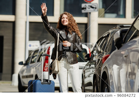 Smiling Young Woman Hailing Cab Smiling Young Woman Hailing Cab 96084272