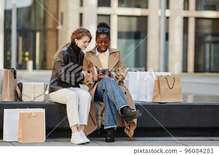 Two Girls Using Smartphone Outside Shopping Mall 96084281
