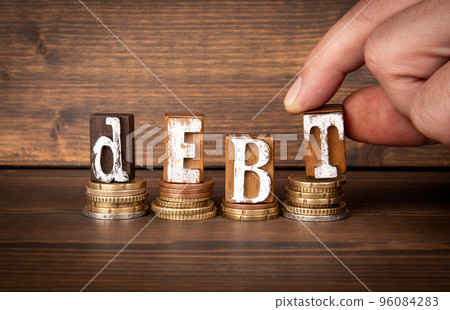DEBT. Wooden letter alphabet blocks and change on wooden background 96084283