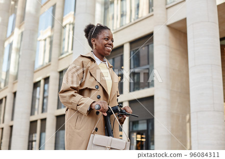 Black Young Woman Using Scooter in City Black Young Woman Using Scooter in City 96084311