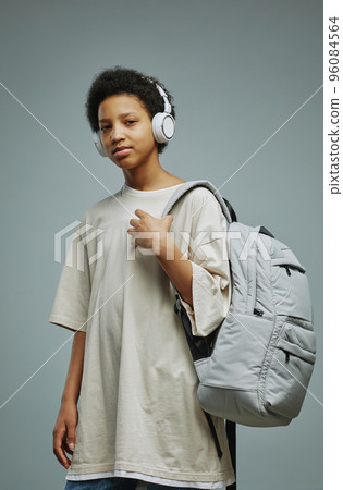Cute schoolgirl in long white t-shirt and headphnes holding backpack Cute schoolgirl in long white t-shirt and headphnes holding backpack 96084564