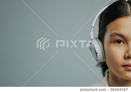 Half of face of adolescent Asian girl listening to music in headpphones 96084567