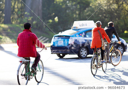 Three adults riding bicycles on a sunny day 96084673