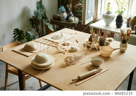 Wooden table in cozy pottery studio setup for ceramics workshop Wooden table in cozy pottery studio setup for ceramics workshop 96085235