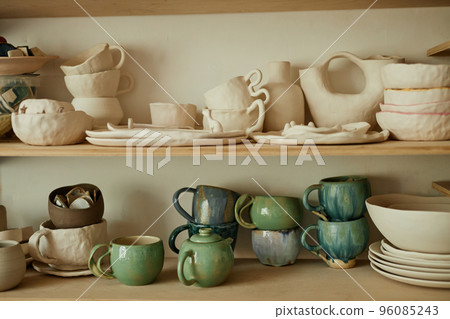 Wooden shelves with handmade ceramic cups and tea sets 96085243