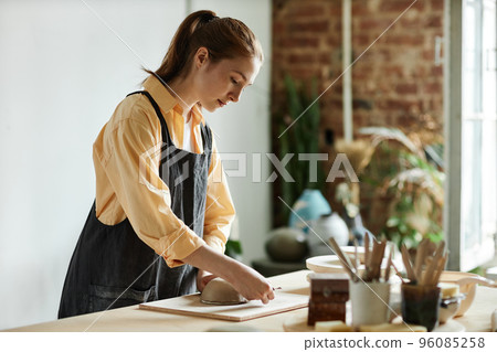 Young woman creating handmade ceramic bowl in cozy pottery studio Young woman creating handmade ceramic bowl in cozy pottery studio 96085258