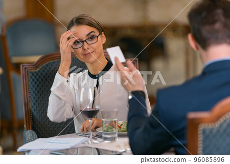 Businessman giving his visit card to woman while having dinner in luxury hotel restaurant 96085896