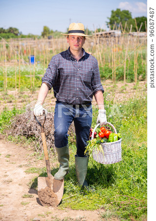 Happy farmer with basket of vegetables in the garden Happy farmer with basket of vegetables in the garden 96087487
