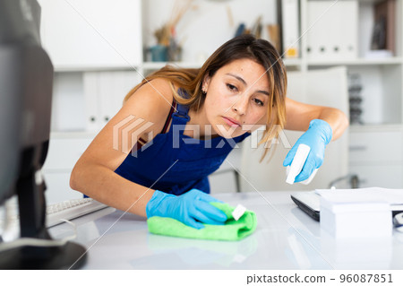Mexican woman wearing uniform cleaning table in office 96087851