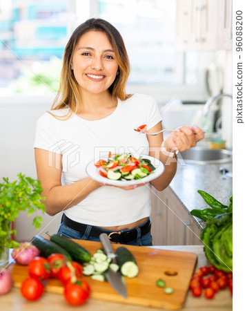 Mexican housewoman eating vegetable salad from plate Mexican housewoman eating vegetable salad from plate 96088200