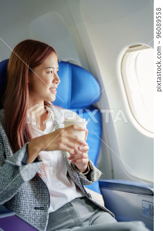 portrait of A successful asian business woman or female entrepreneur in formal suit in a plane sits in a business class seat and drink coffee during flight, relax concept. 96089558