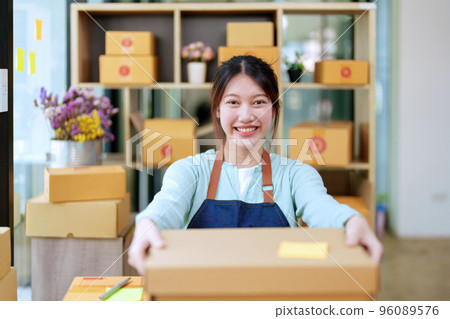 Portrait of a business woman, sme packing products in boxes and showing delivery to customers according to their orders. Portrait of a business woman, sme packing products in boxes and showing delivery to customers according to their orders. 96089576