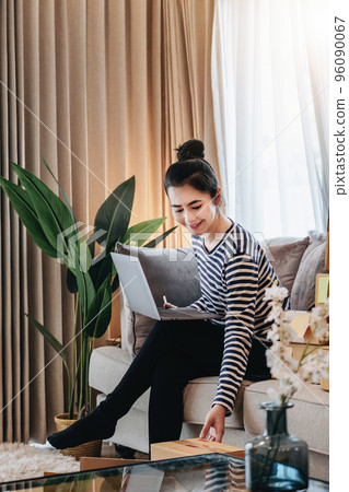 Online merchandising business idea, a beautiful girl is using a computer to check orders to deliver parcels to customers according to orders received from customers 96090067