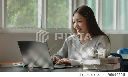 Happy young Asian student girl using laptop in university campus or at virtual office. College female student remote learning. Happy young Asian student girl using laptop in university campus or at virtual office. College female student remote learning. 96090336