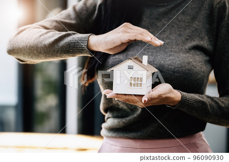 Real estate agent gesturing to protect homes, housing insurance concept 96090930