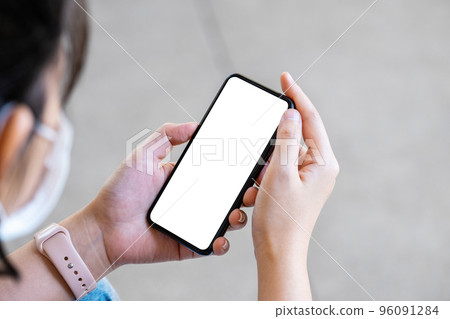 A woman holding a cell phone with a blank white screen. The blank space on the white screen can be used to write a message or place an image 96091284