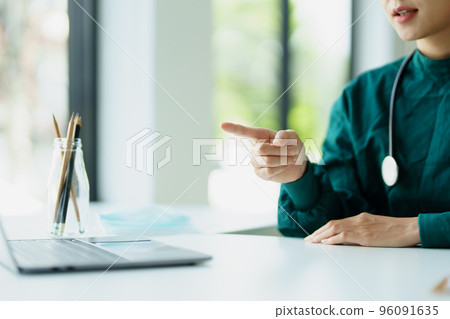 Portrait of an Asian doctor using a computer to look at patient data to analyze symptoms before treatment. 96091635